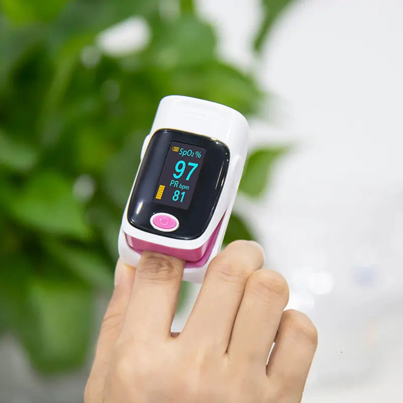 Finger pulse oximeter on a person's finger with a blurred green background