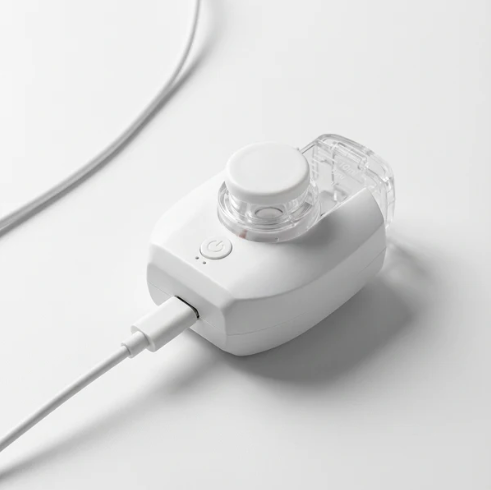 A white and clear handheld nebuliser shown charging