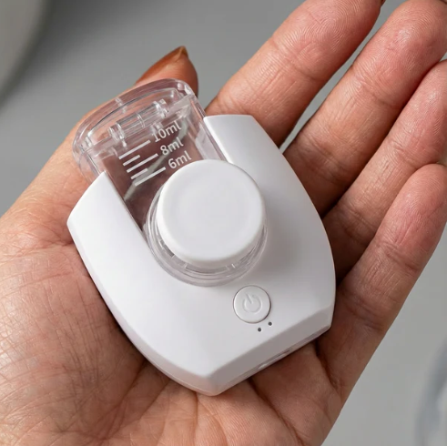 A white and clear handheld nebuliser shown on a in a hand.