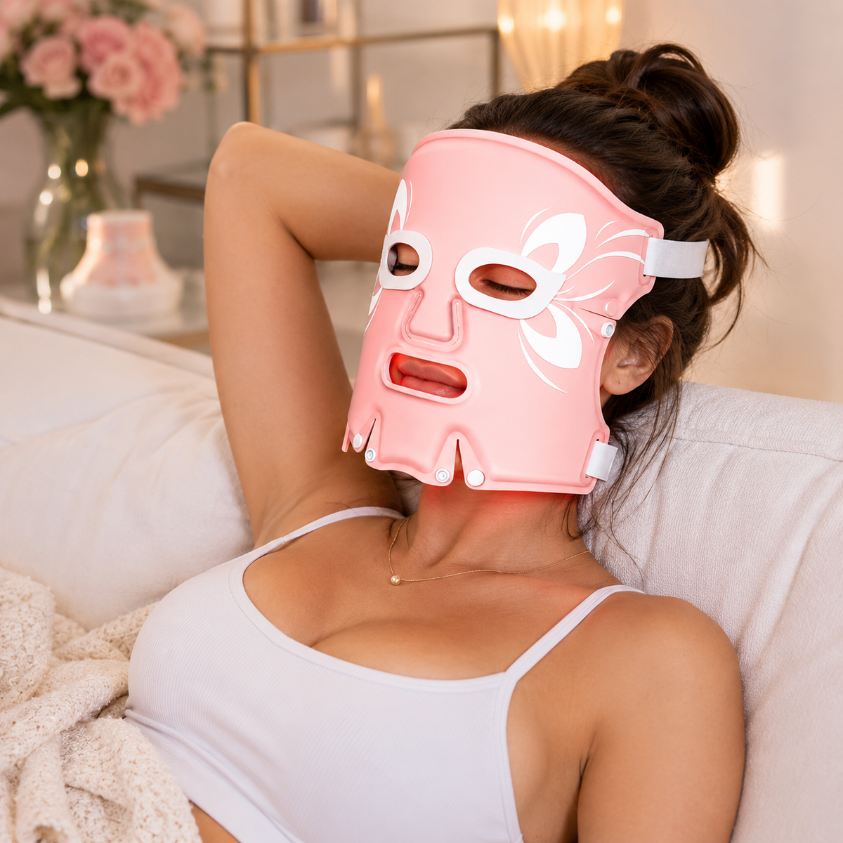Woman wearing a pink facial mask with white floral design on a couch.